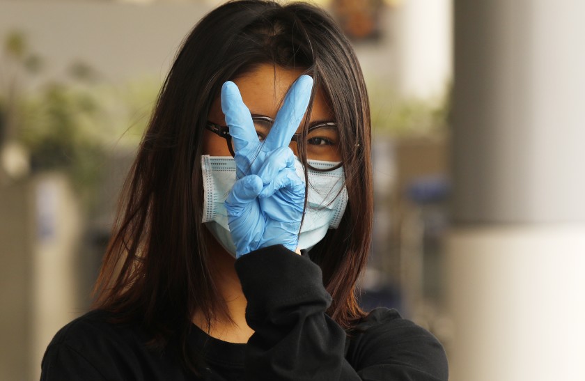 Young woman wearing mask flashes victory sign