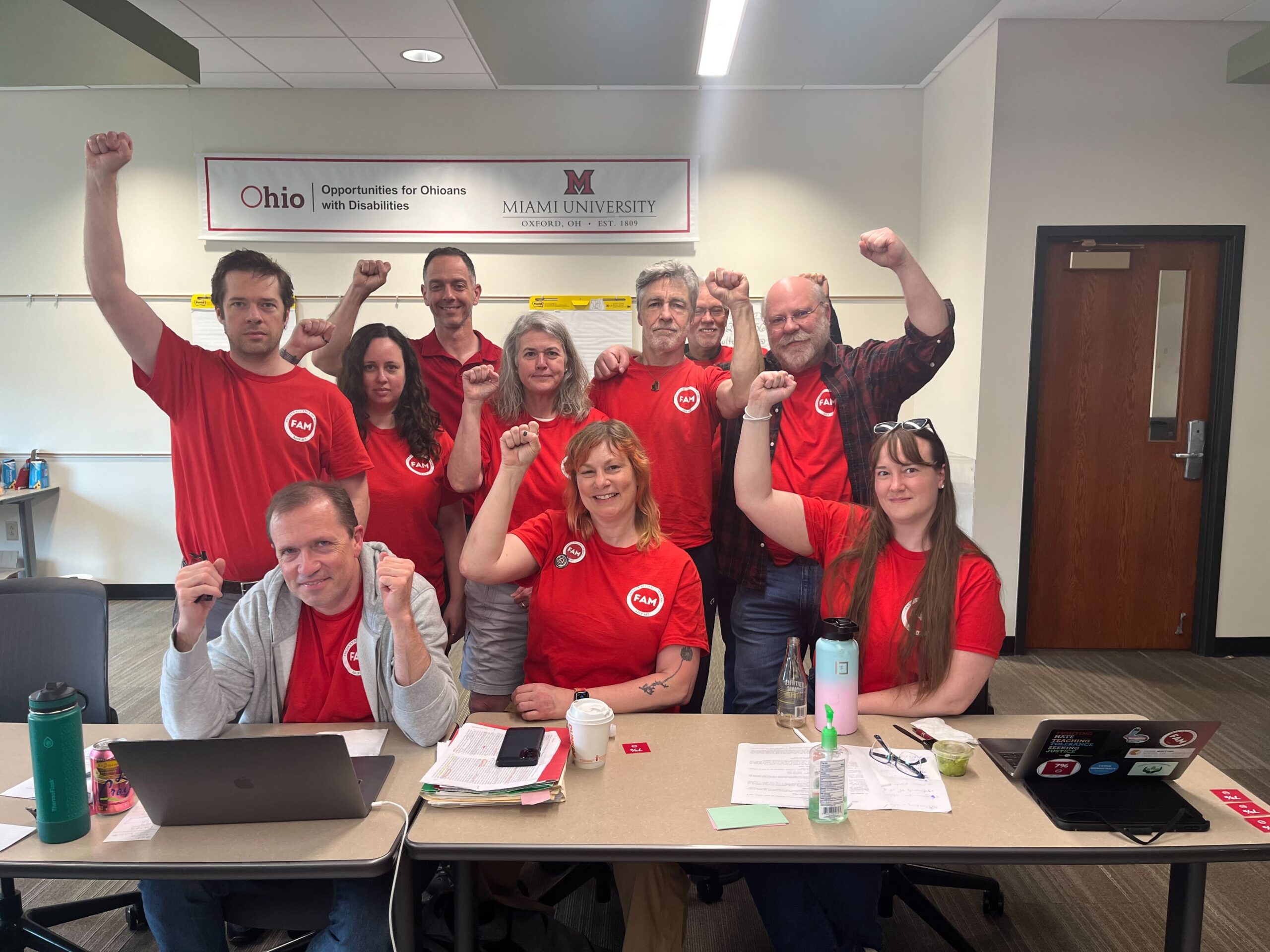 FAM's Negotiating Team, decked out in red, fists raised in solidarity