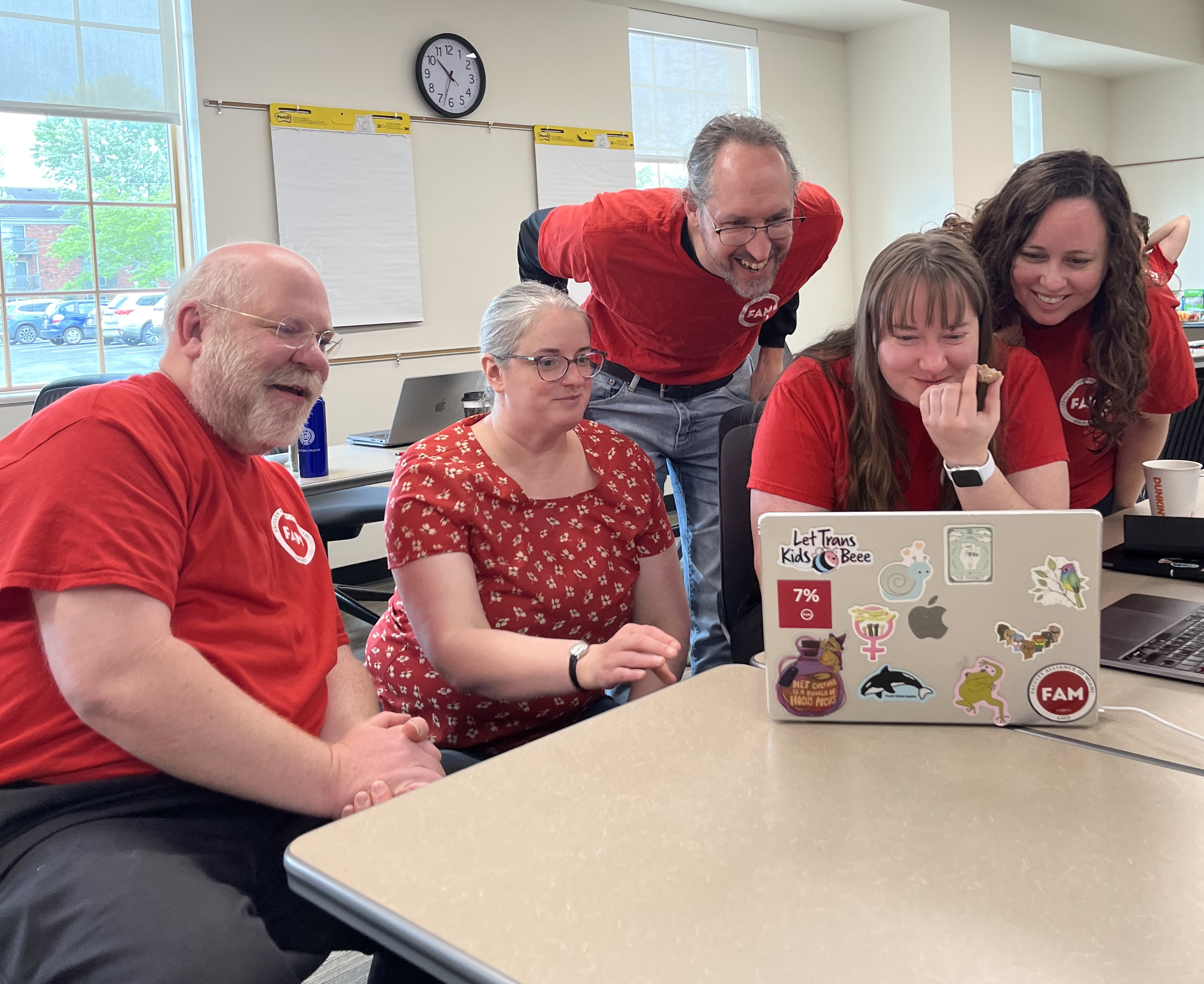 Librarians in solidarity red gather around a laptop