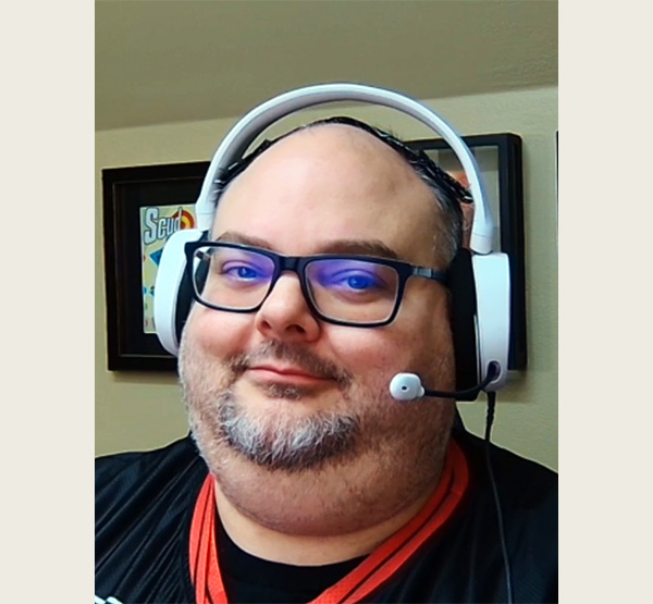 Phill Alexander smiling in glasses and headphones