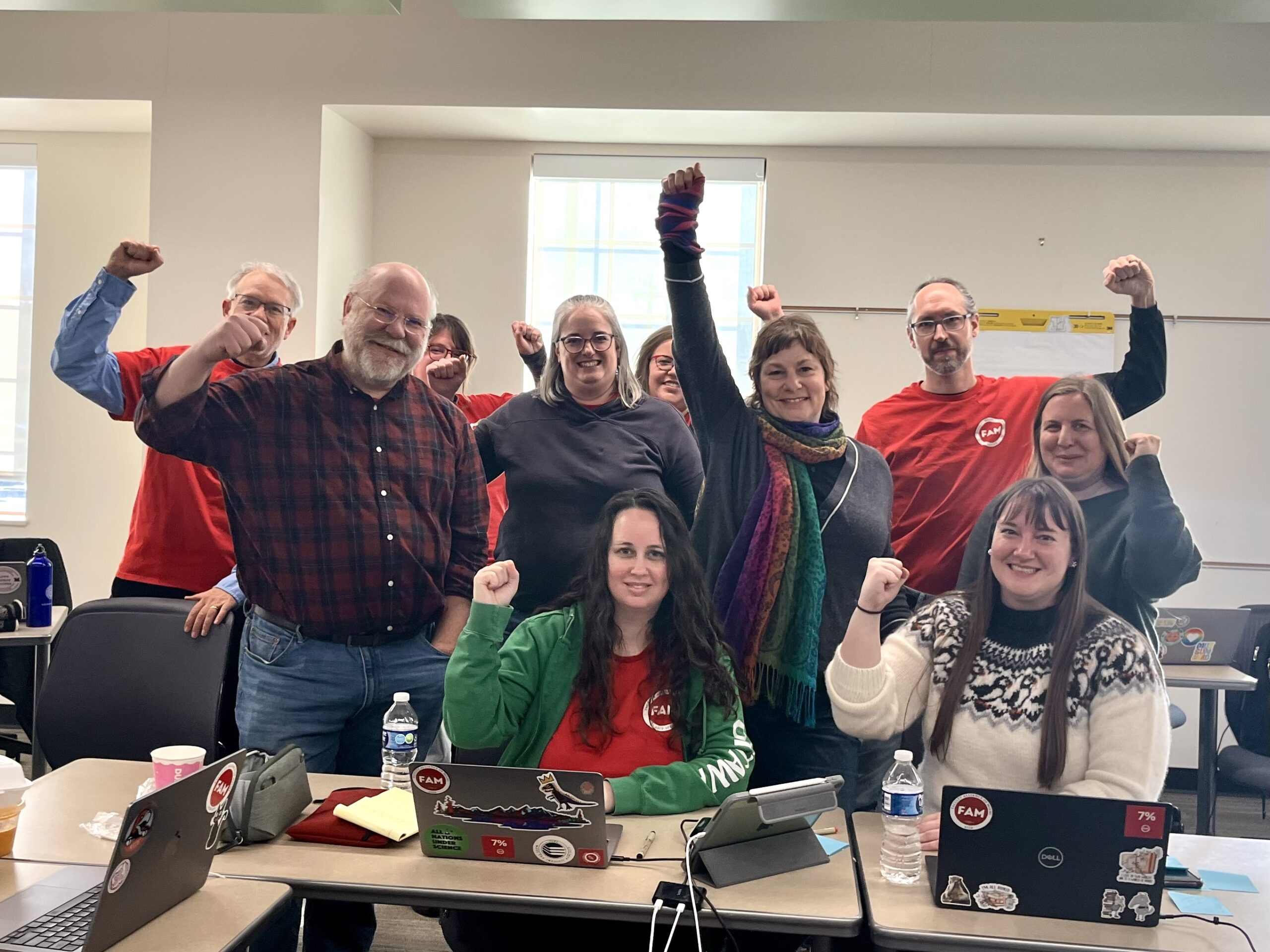 A colorful gang of smiling NT members and librarians, fists raised in solidarity, smiling.