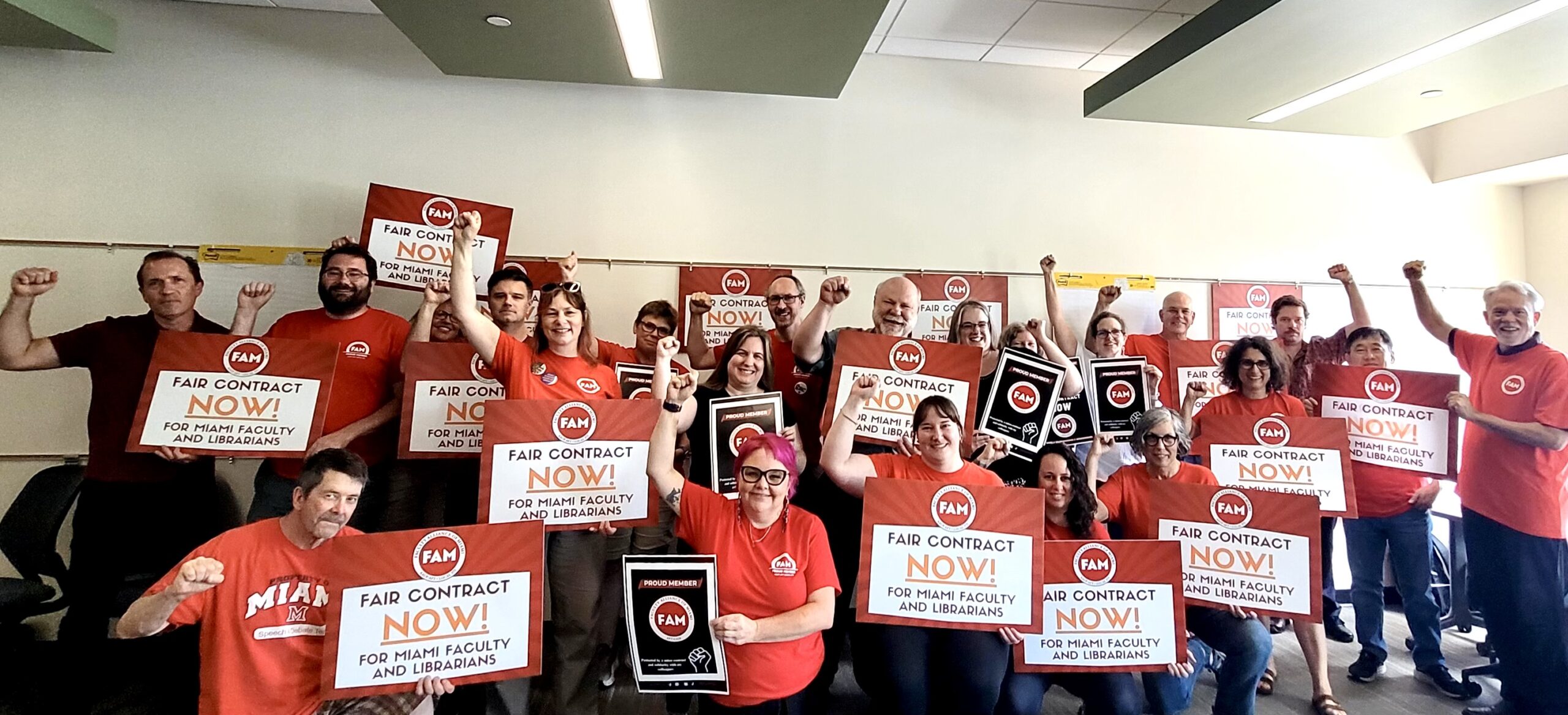 A group of FAM faculty and librarians hold FAIR CONTRACT NOW signs and raise solidarity fists!